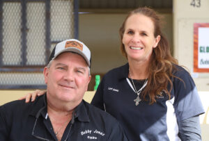 Headshot of Bobby (left) and Lori (right) Jones. They smile for the camera in front of one of the OBS Sales’ barns. (Photo: ©OBS)