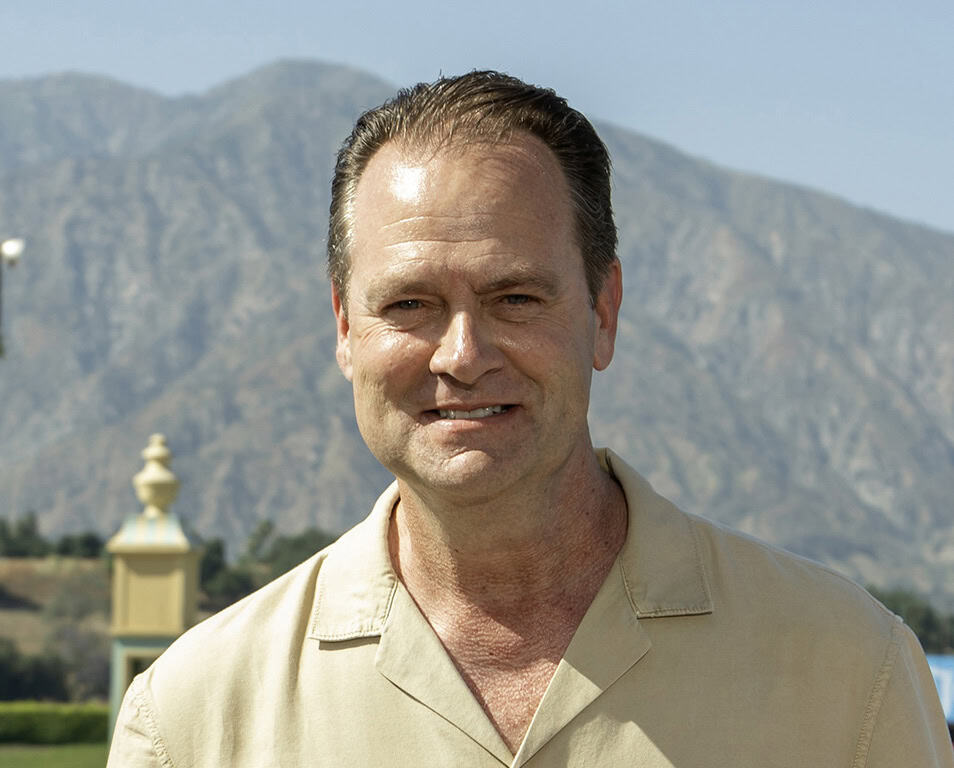 Headshot of Trainer Doug O'Neill smiling for the camera trackside. (Photo: ©Benoit)