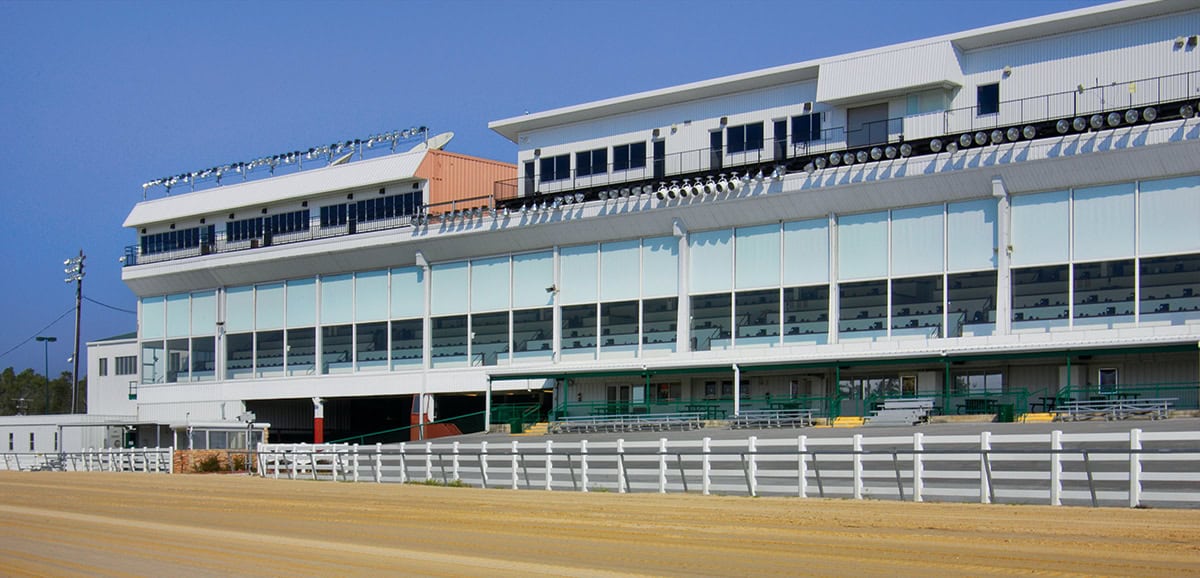 Photograph taken of the Delta Downs Grandstands. The sky is clear, but the track in front of the Grandstands is wet from rain. (Photo: ©Boyd Gaming)