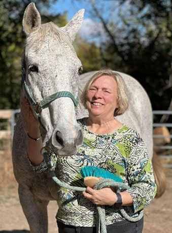 FTBOA Member Vickie Nitschke stands with House of Words, a grey Thoroughbred resident of Unbridled Spirits, who Vickie sponsors.