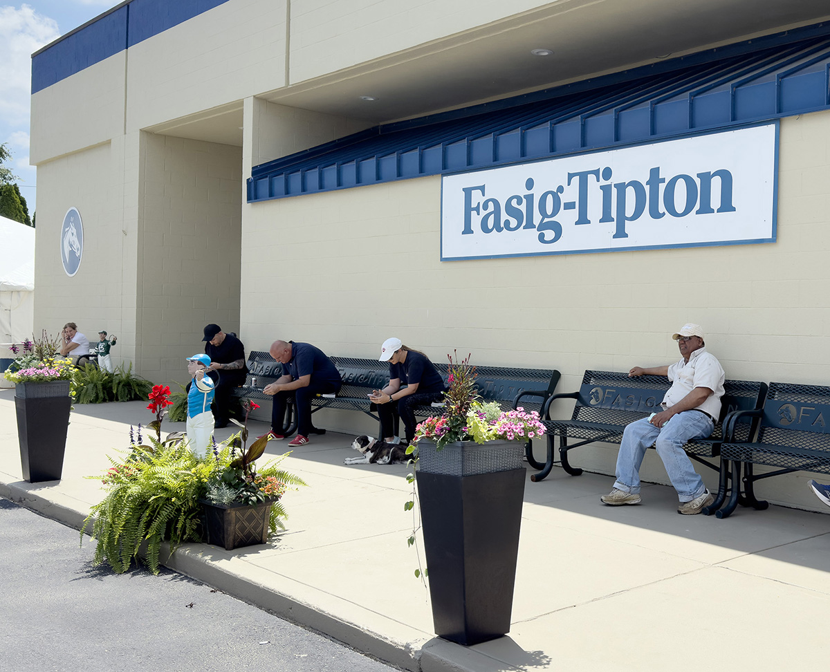 A group of auction goers taken a moment to rest in the shade next to one of the buildings on ground at Fasig-Tipton during the Fasig-Tipton Midlantic May Two-Year-Olds-in-Training Sale. (Photo: ©Fasig-Tipton Photo)