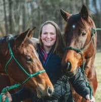 Photo of Dr. Megan Knoell standing with two of her horses. She has a lead in both hands and smiles for the camera as one horse leans around her and the other looks across from her with curious, pricked ears. (Photo Courtesy: TRF) 