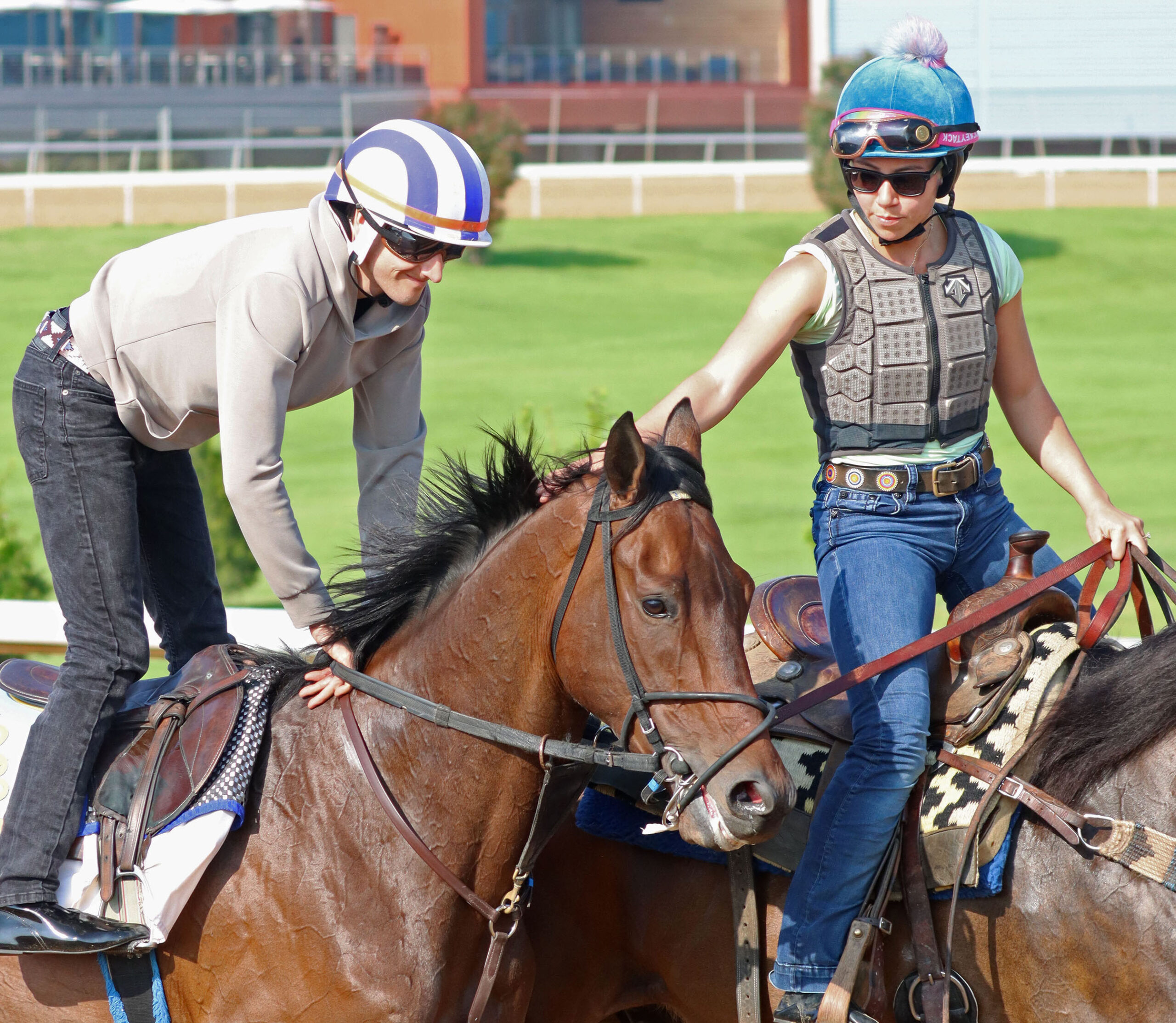 Closely cropped photo of Redland Rebels being ponied during a morning exercise. The person ponying Redland Rebels reaches over to pet him behind his ears from her horse, while his exercise rider smiles. (Photo: ©Cady Coulardot / Coady Media)