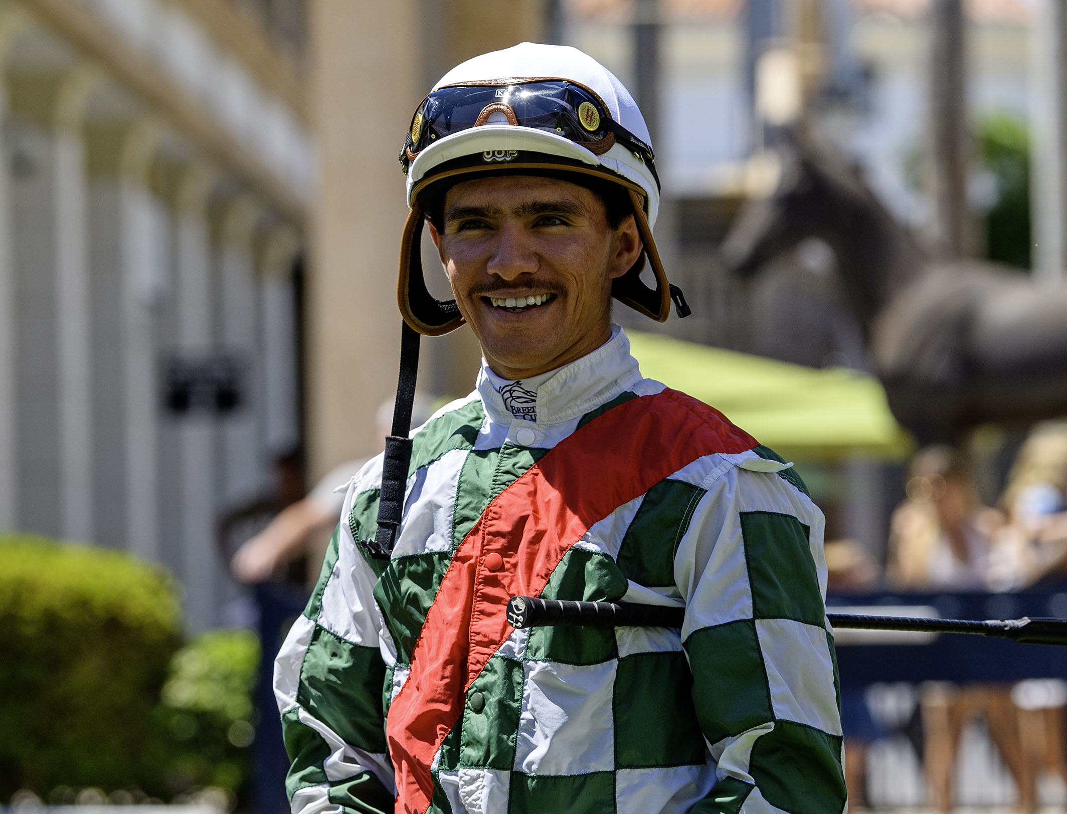 Jockey Diego Herrera smiles for the camera trackside, dressed in green and white checkered silks. (Photo: ©Ryan Thompson)