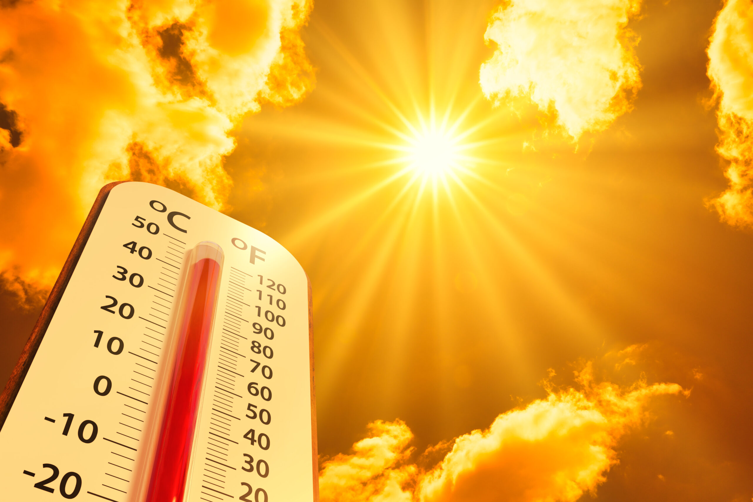 A blazing sun shines downwards from the sky, implied to be so hot the sky is turned orange. A thermometer looms up from the edge of the photo, measuring temperatures of over 100 degrees and climbing. (Photo: ©Iamyal)