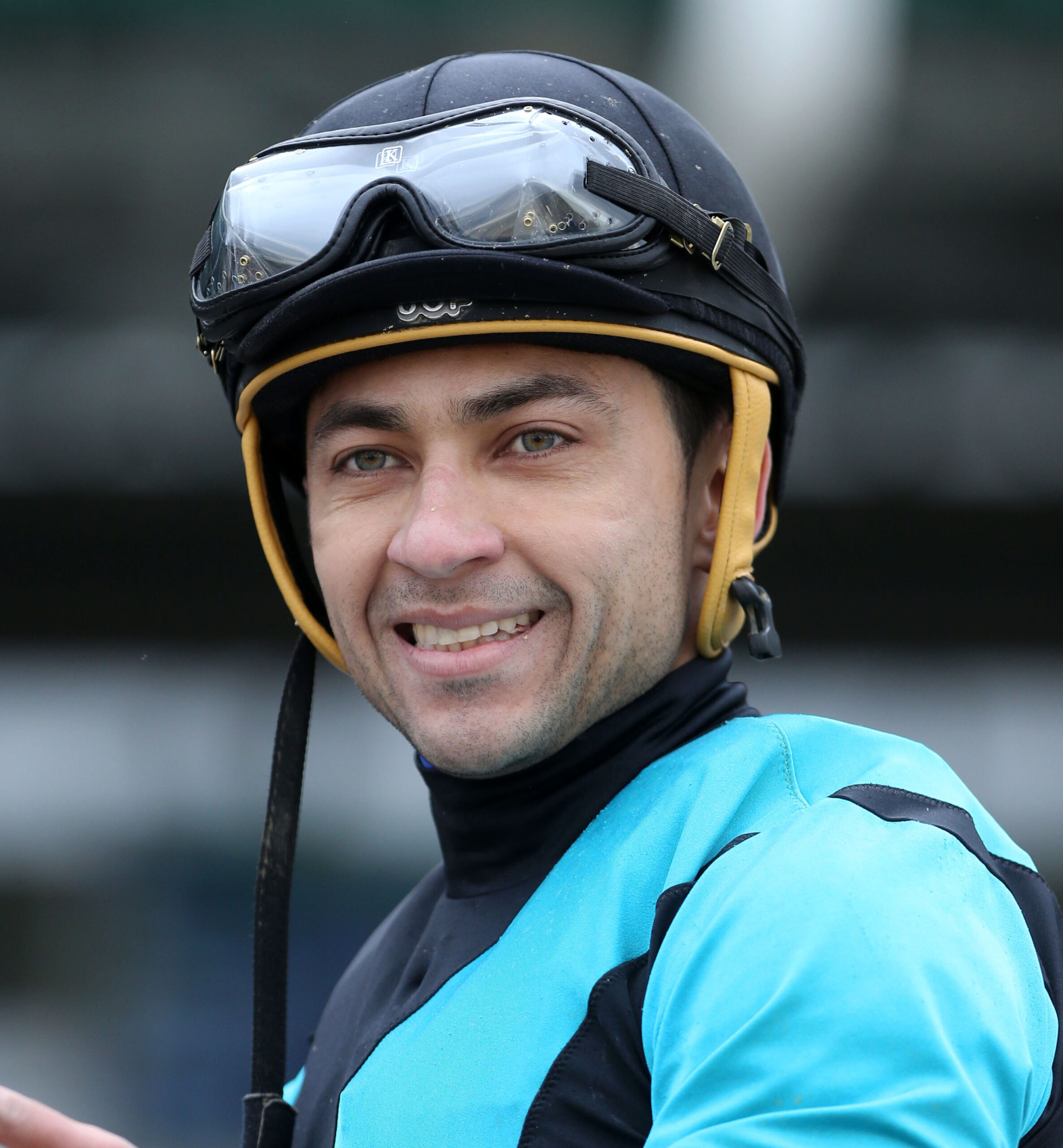 Headshot of jockey Sonny Leon smiling for the camera post race dresses in blue and black silks. (Photo: ©Coady)