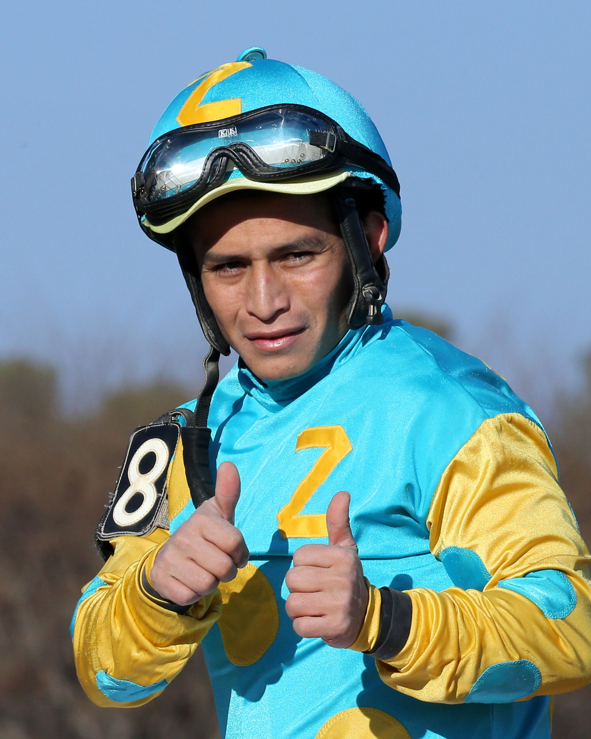 Jockey Walter De La Cruz flashes a thumbs up at the camera while wearing blue and yellow silks. (Photo: ©Coady Media)