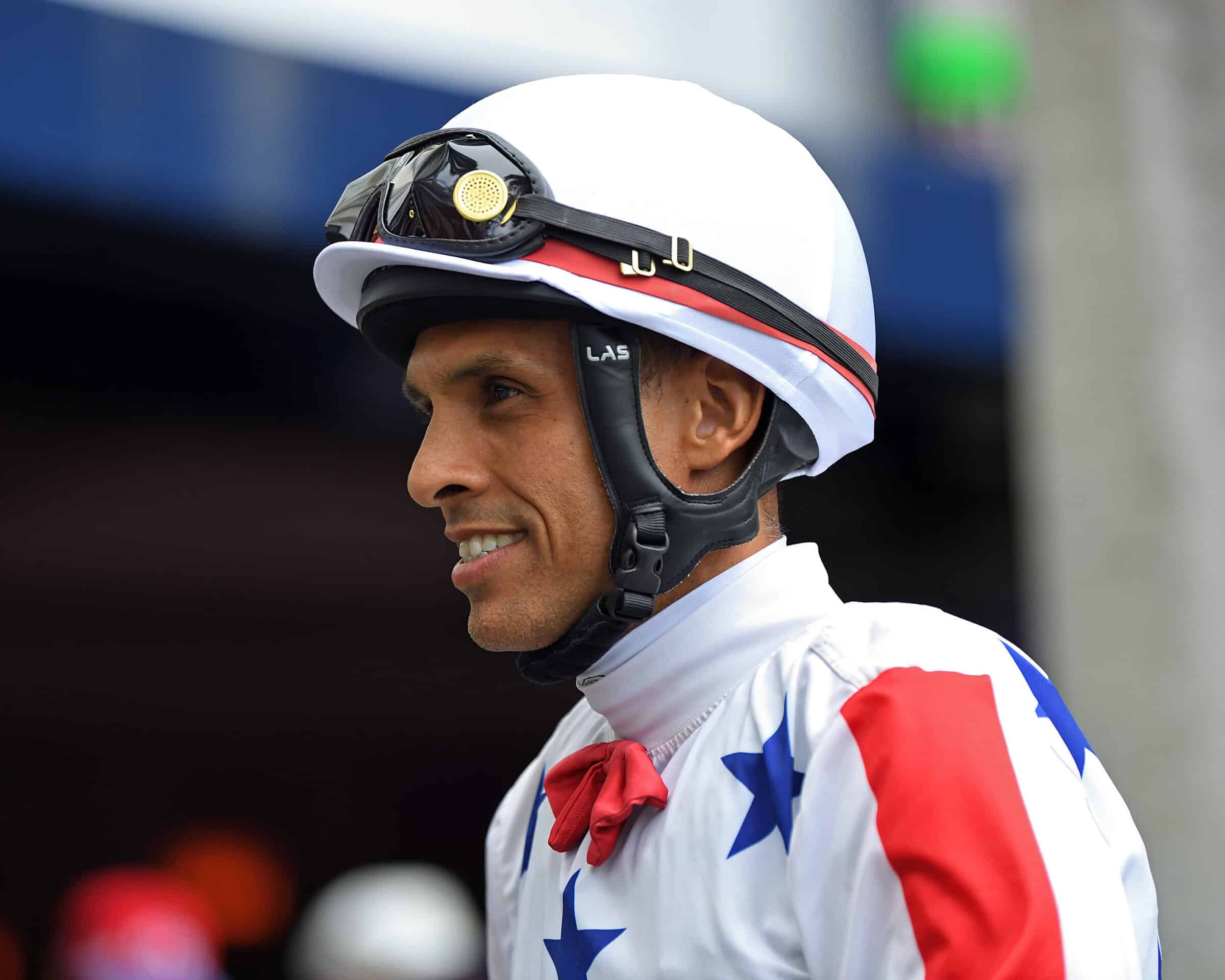 Jockey Pedro Monterrey Jr. looks left in his jockey helment and white, orange and blue silks