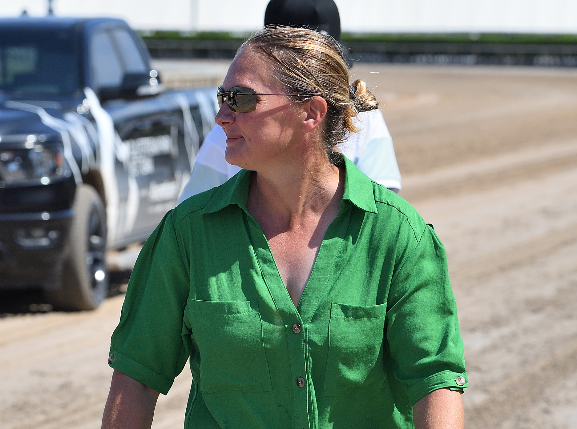 Headshot of trainer Heather Smullen looking over her shoulder as she walks off the Thoroughbred race track. (Photo: ©Ryan Thompson)