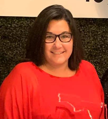 Headshot of trainer Mary Lightner, wearing a bright red shirt and glasses, smiling for the camera. (FTBOA file photo.)