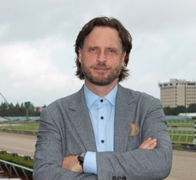 Professional headshot of Aidan Butler, standing against the backdrop of Gulfstream Park. (Photo: ©Ryan Thompson)