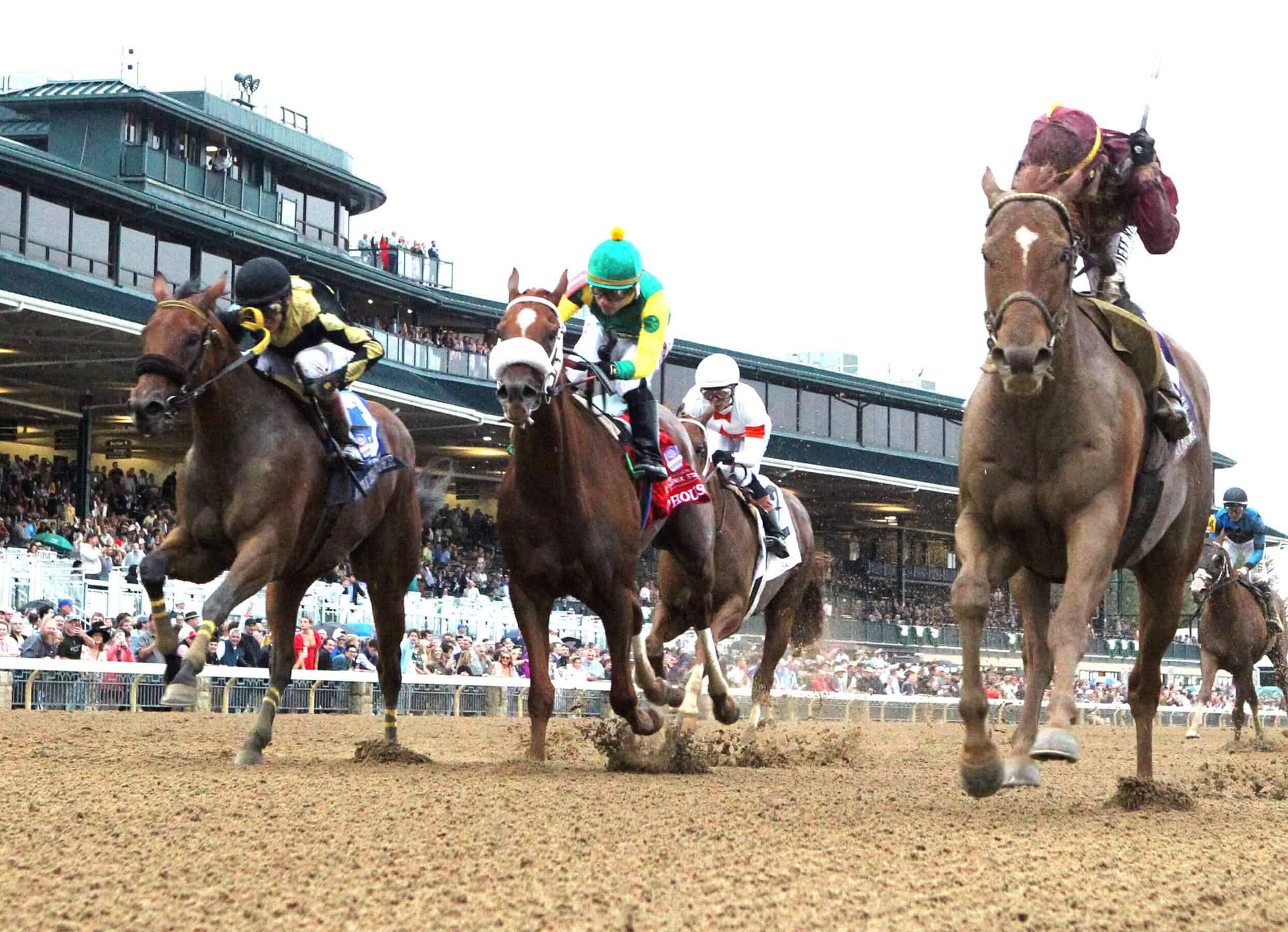 A cluster of Thoroughbreds gallop three-wide in front of the Keeneland grandstand. Florida-bred Thoroughbred Little Thunder and jockey John Velazquez (far left) gallops on the outside with fellow Florida-bred Mad House and jockey Sonny Leon galloping in the middle, keeping pace with inside competitor Nakatomi, piloted by jockey Irad Ortiz, Jr., won the 2026 Grade 2 Stoll Ogden Phoenix while the Florida-breds finished just noses apart in second and third, respectively. (Photo: ©John Gallagher/Coady Media)